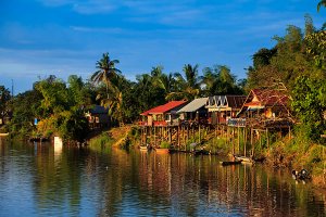Guesthouses and restaurants on the banks of the Mekong River at sunset, located on Don Det Island which forms part of the Four Thousand Islands, known locally as Si Phan Don.