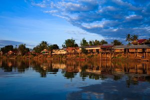 Guesthouses and restaurants on the banks of the Mekong River at sunset, located on Don Det Island which forms part of the Four Thousand Islands, known locally as Si Phan Don.