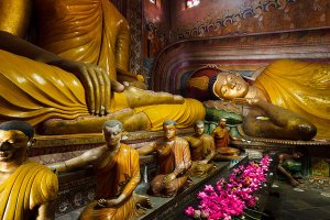 Large reclining Buddha statue inside the main image house of the late nineteenth century Wewurukannala Vihara Temple, surrounded by smaller seated statues, located in the town of Dikwella.