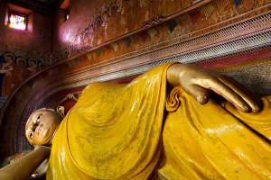 Large reclining Buddha statue inside the main image house of the late nineteenth century Wewurukannala Vihara Temple, surrounded by smaller seated statues, located in the town of Dikwella.