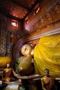 Large reclining Buddha statue inside the main image house of the late nineteenth century Wewurukannala Vihara Temple, surrounded by smaller seated statues, located in the town of Dikwella.