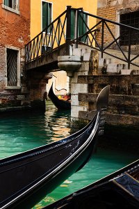 Gondolier taking tourists on gondola boat ride on the narrow canals of the UNESCO World Heritage Site of Venice.